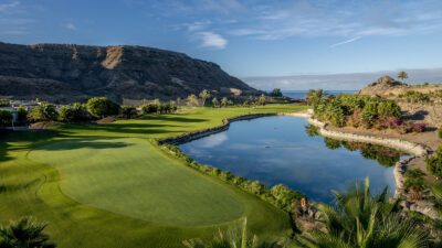 picture of anfi tauro golf course with a lake and a mountain in the background