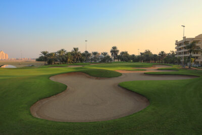 Bunkers on fairway with palm trees and building in the distance