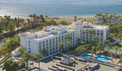 Aerial view of ME Marbella with sandy beach in the background and trees around