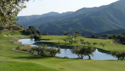 Lake on fairway with trees around and mountains in the distance