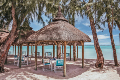 Outdoor dining with private straw gazebos on the beach, overlooking clear waters
