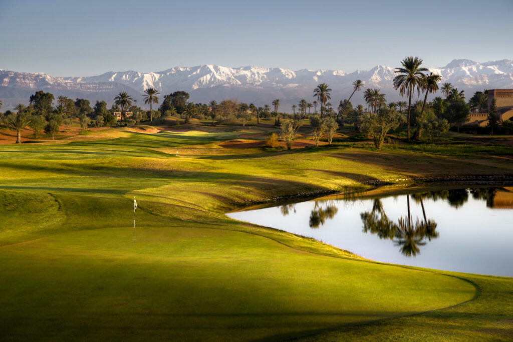 Green with lake to the right and mountains on the horizon at Amelkis Golf Course