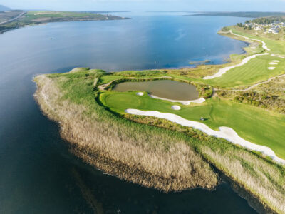 Aerial view of a hole at Arabella Country Estate with bunkers and lake next to it with ocean view