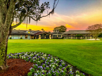 Exterior of Arnold Palmers Bay Hill Club at sunset with trees and flowers around