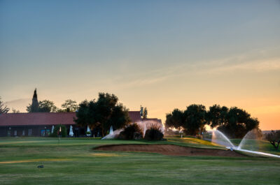 Bunker with sprinklers on and building in the background at Benamor golf course