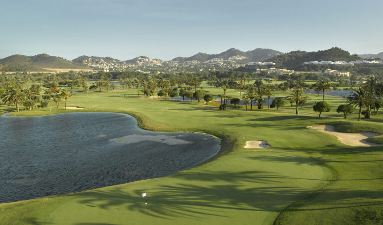 Hole with lake next to it and bunkers around, with trees dotted around and hills in the distance
