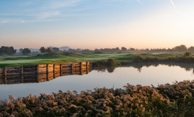 Lake on fairway with trees in distance at Emporda Golf