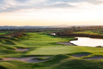 Hole with a white flag, bunkers and a lake around at Emporda Golf