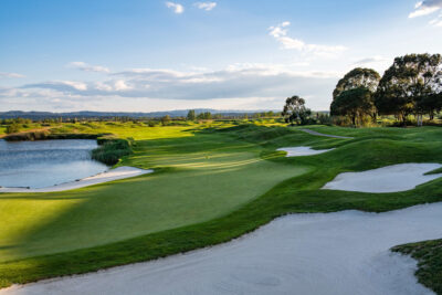 Bunkers on fairway near a hole with a yellow flag with trees and a lake around
