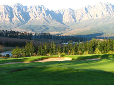 Hole with white flag with bunkers and trees around with mountains in the distance