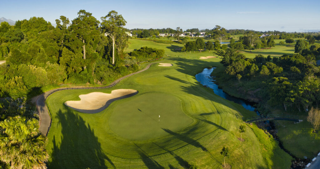 Aerial view of a hole with a white flag and bunker with trees around
