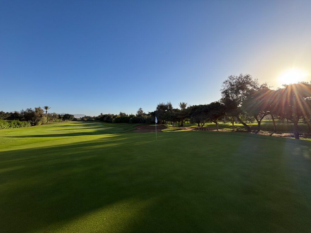 Greenside with sun creeping over trees at Golf du Soleil