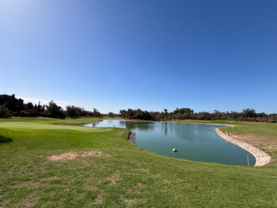Green with lake and blue skies at Golf Les Dunes Course