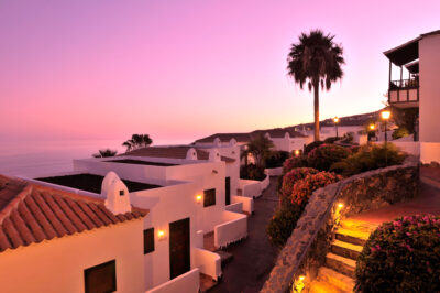 White buildings dimly lit up in the evening with a pink sky