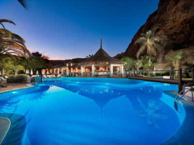 Outdoor pool at Hotel Jardin Tecina lit up in the evening with palm trees around