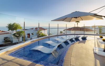 White loungers in a shallow pool with view of white buildings and ocean