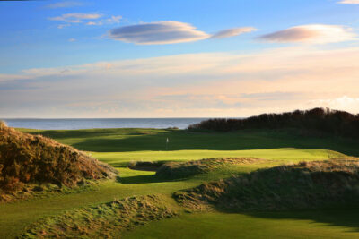 Hole at Championship Links at Royal County Down with mounds around with ocean view