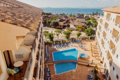 View of the outdoor swimming pool with the hotel balcony rooms, with the ocean in the distance