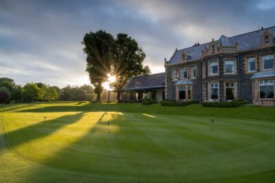 Practice area with Malone Golf Clubhouse and trees in background