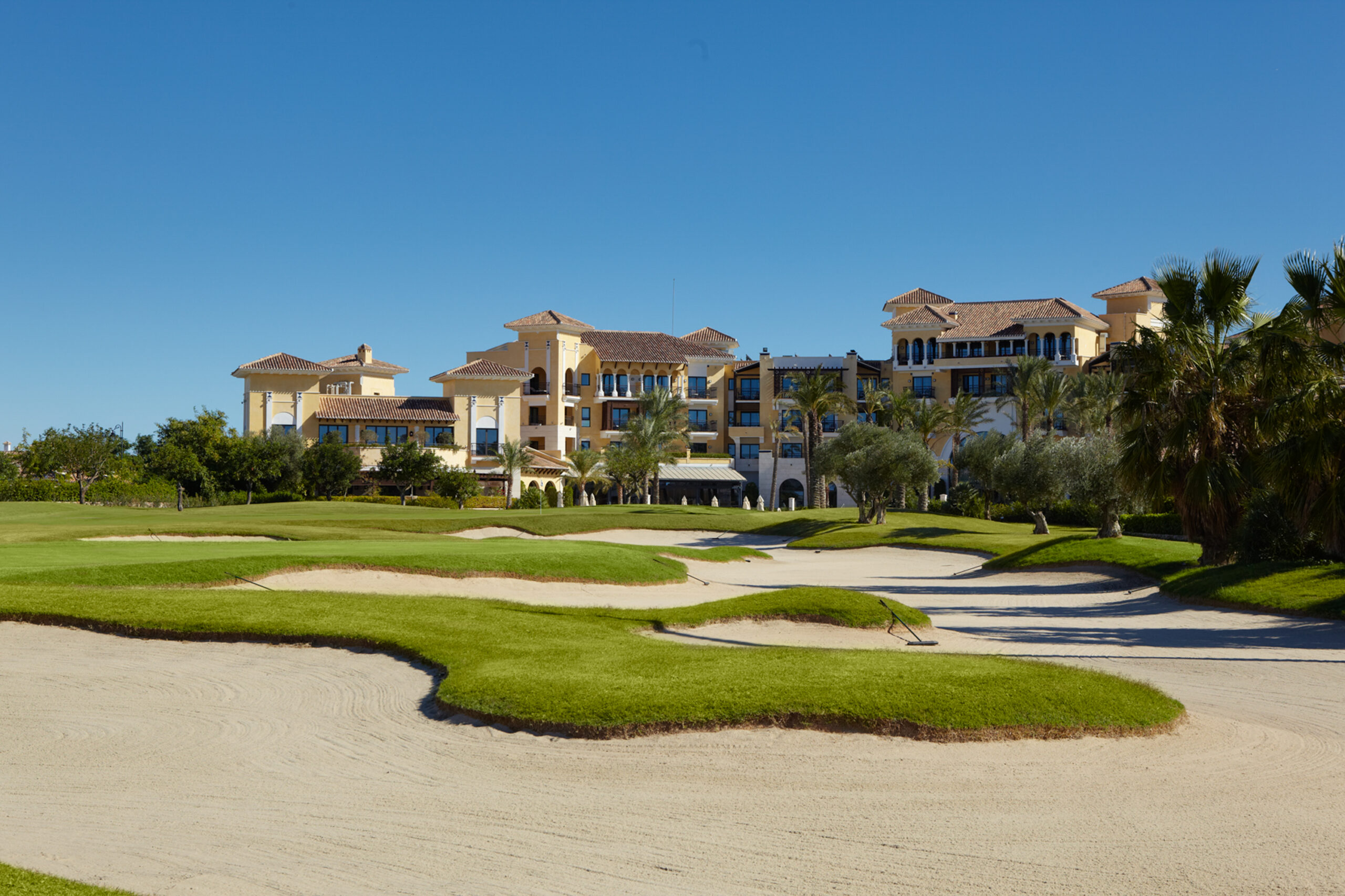Bunkers on fairway with buildings in background and trees around