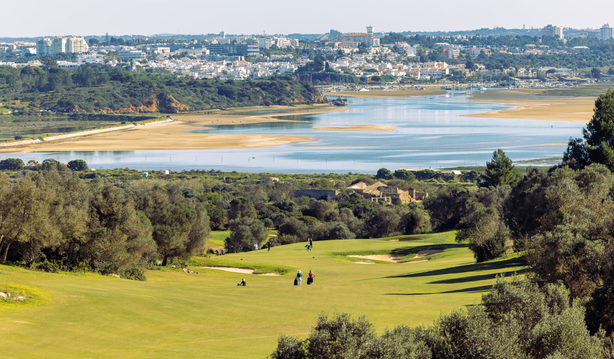 People playing golf at Palmares Golf Course with lake and town in background at Palmares Golf Course