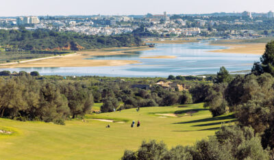 People playing golf at Palmares Golf Course with lake and town in background at Palmares Golf Course