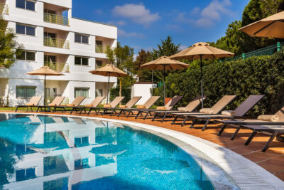 Outdoor pool wuth sun loungers and hotel in background at Patio Suite Hotel