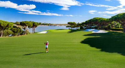 Woman playing golf at Quinta Do Lago South Golf Course with a lake in the background