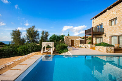 Outdoor pool with white curtained sun beds and trees around
