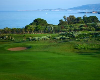Fairway with bunker and trees around with ocean in background