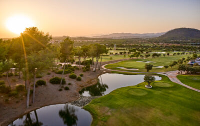 Aerial view of golf course with water hazards and bunkers with trees around at sunset