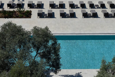 Outdoor pool with black loungers around and trees