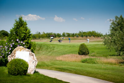 People playing golf at Lighthouse Golf Course with trees around