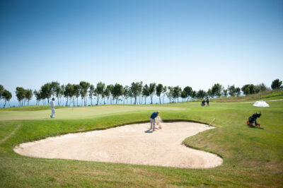 People playing golf at Lighthouse Golf Course with trees in the background