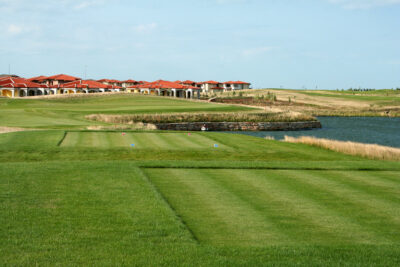 Tee box with a lake next to it with buildings in the background