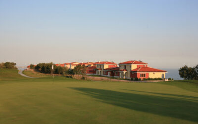 Hole with white flag with buildings in the background at Lighthouse Golf Course