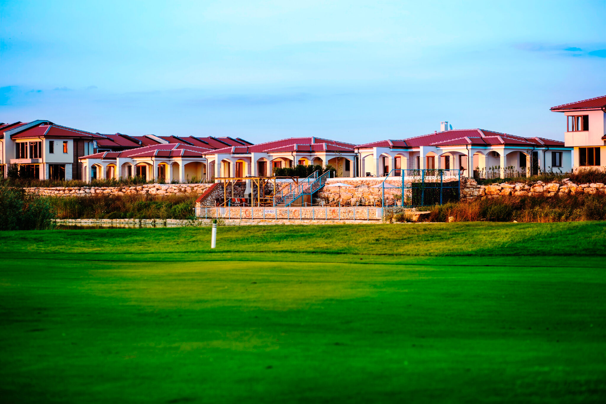 Exterior of the Lighthouse Golf Club with a red tiled roof and a green in the foreground
