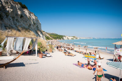 People relaxing on the beach with sun loungers and straw umbrellas
