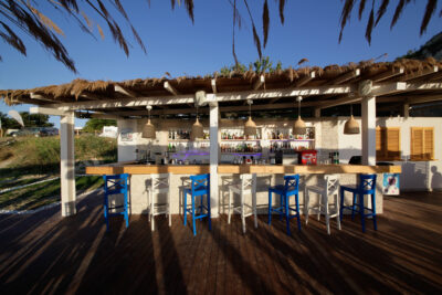 Outdoor bar with blue and white stools and a thatched roof