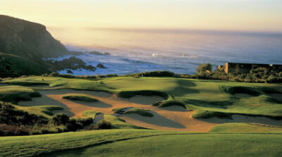 Bunkers surrounding a hole with a white flag on a clifftop overlooking the ocean