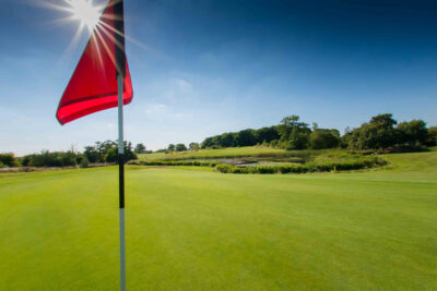 Hole with red flag at Whittlebury Park Golf Course with trees in background