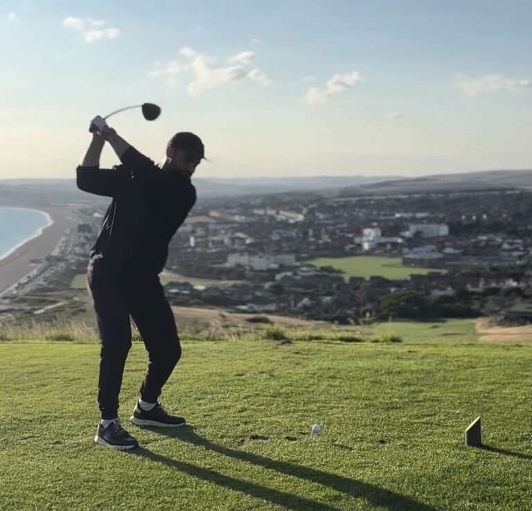 a golfer on the tee with a city in the background