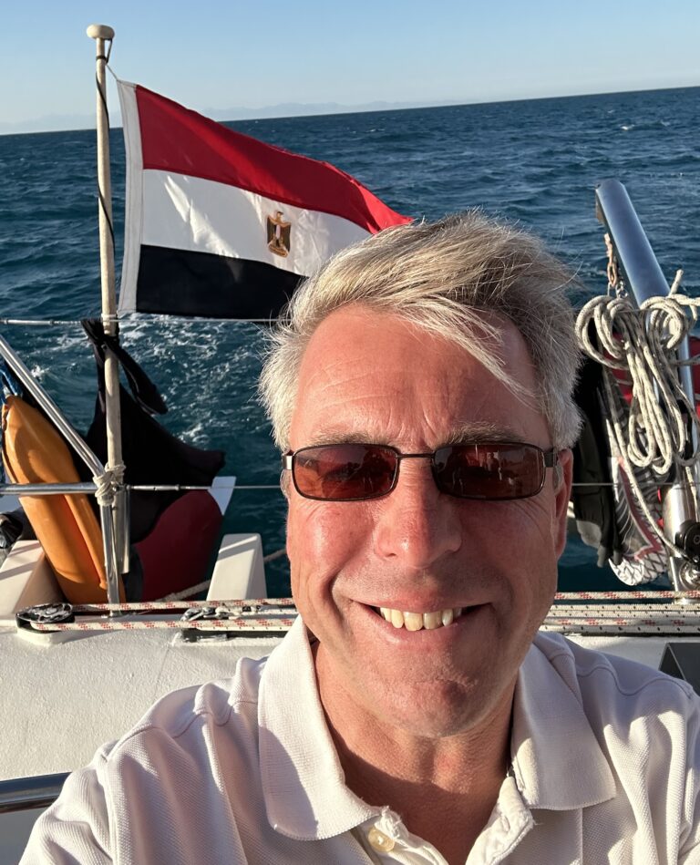 a man on a boat in the sea with the Egyptian flag behind him