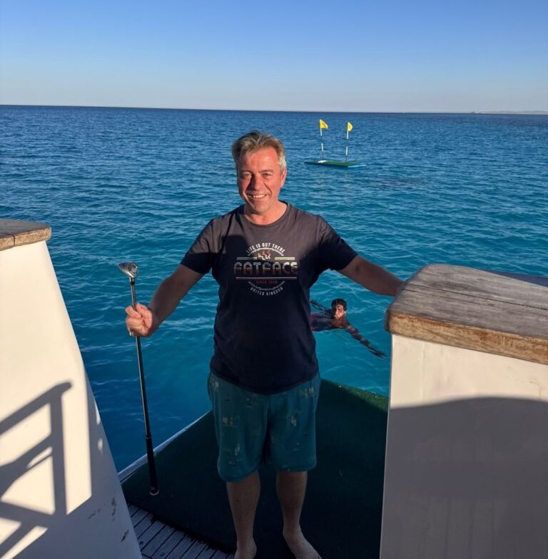 a man on a boat with the sea behind him